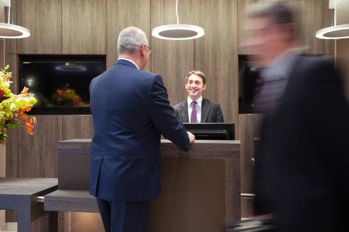 a man in a suit shaking hands at a counter at Mercure Hotel Brussels Centre Midi in Brussels