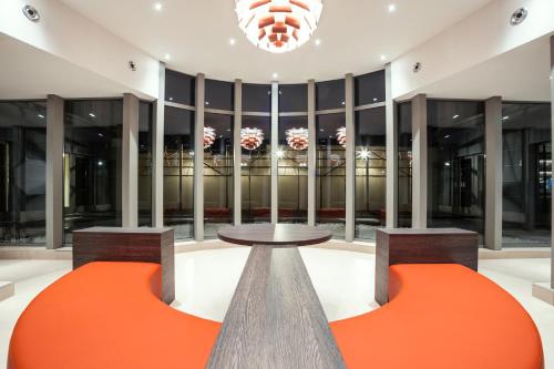 a lobby with two orange chairs and a table at Mercure Hotel Brussels Centre Midi in Brussels