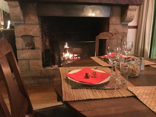 een tafel met een rood servet en een open haard bij Les chambres de la Dourbie in Nant
