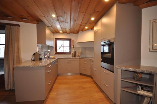 a kitchen with white cabinets and a wooden ceiling at Chasa Sager 2 in Scuol