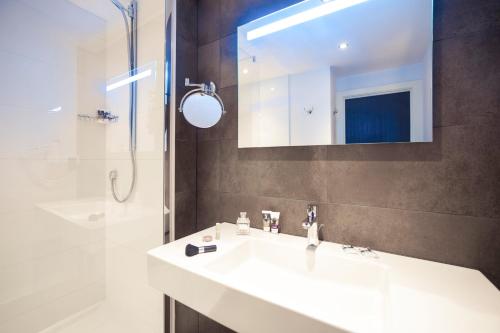 a bathroom with a white sink and a shower at Mercure Hotel Brussels Centre Midi in Brussels