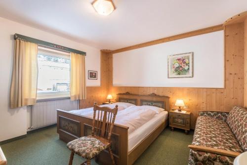 1 dormitorio con 1 cama, 1 silla y 1 ventana en Kleine Gartenwohnung Haus Forelle, en Selva di Val Gardena