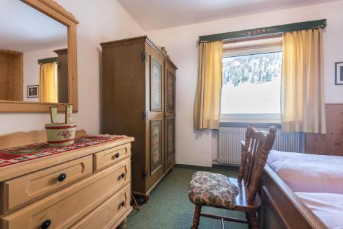 a bedroom with a dresser and a bed and a window at Kleine Gartenwohnung Haus Forelle in Selva di Val Gardena