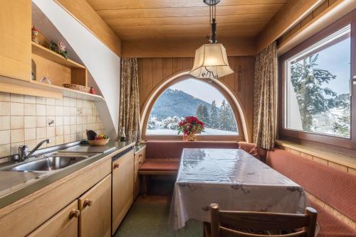 eine Küche mit einem Waschbecken und einem Bogenfenster in der Unterkunft Kleine Gartenwohnung Haus Forelle in Wolkenstein in Gröden