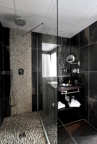 a bathroom with a glass shower with a sink at Hôtel Arles Plaza in Arles