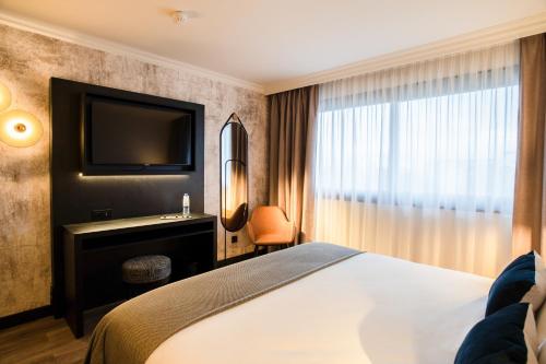 una camera d'albergo con un letto e una televisione di Appart'City Collection Genève Aéroport - Ferney Voltaire a Ferney-Voltaire