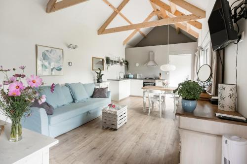 a living room with a blue couch and a kitchen at Woubrugge Logies in Woubrugge