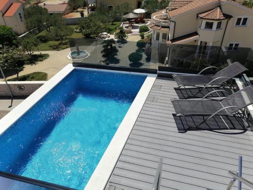 a swimming pool on a deck with chairs and a house at Villa Lio I in Vodice