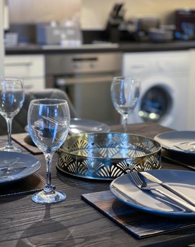 a wooden table with plates and wine glasses on it at Station Side Penthouse in Wolverhampton