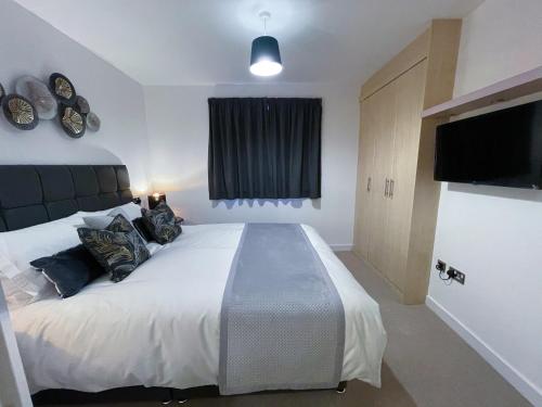 a bedroom with a large bed and a flat screen tv at Station Side Penthouse in Wolverhampton