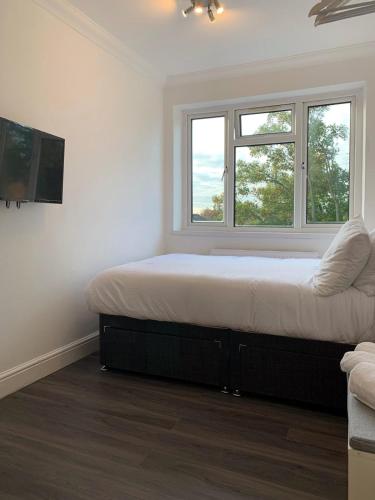 a bedroom with a bed and two windows at Luxury Suites near Wembley Stadium, Wembley Arena, London Designer Outlet in London