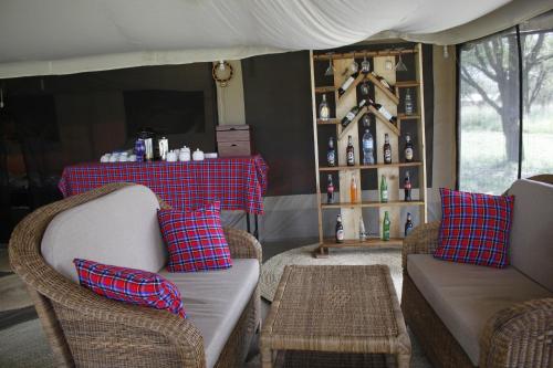 a living room with two couches and a table with wine bottles at Osero Serengeti Luxury Tented Camp in Banagi