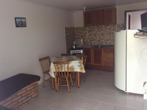eine Küche mit einem Tisch mit Stühlen und einem Kühlschrank in der Unterkunft Pousada do Mar in Rio Grande