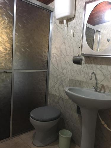 a bathroom with a toilet and a sink and a mirror at Casa da Dona Ilda in Pirenópolis