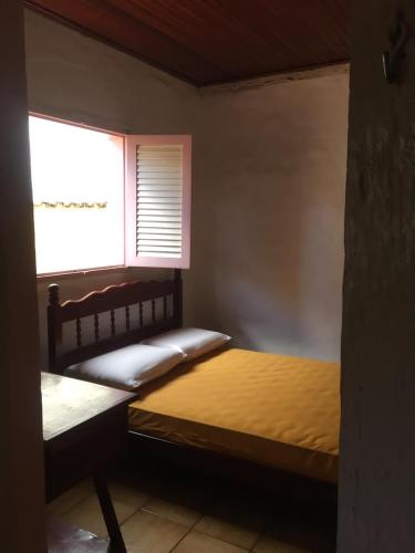 a small bedroom with a bed and a window at Casa da Dona Ilda in Pirenópolis