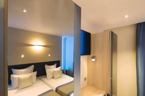 a hotel room with a bed with white pillows at Hôtel Brésil Opéra SPA in Paris
