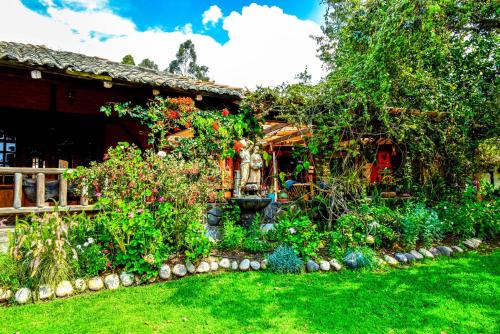 a garden in front of a house with flowers at Hacienda Jimenita Wildlife Reserve in Puembo