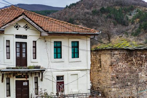 an old white house with a mountain in the background at Etno House Shancheva in Kratovo