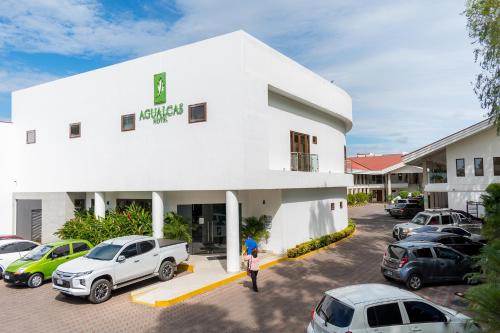 a white building with cars parked in a parking lot at Hotel Agualcas in Managua
