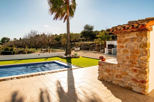 een villa met een zwembad en een palmboom bij FINCA ROMER in Benissa