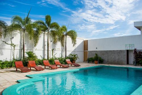 basen z krzesłami i palmami obok budynku w obiekcie Hotel Agualcas w mieście Managua