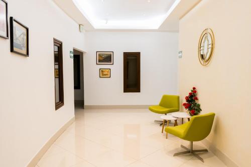 a hallway with two chairs and a table and a clock at Hotel Agualcas in Managua