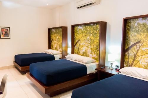 two beds in a room with two windows at Hotel Agualcas in Managua