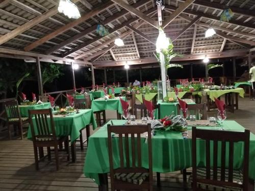 a banquet hall with green tables and chairs at Hotel Praia Inhame Ecolodge in Porto Alegre
