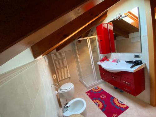 La salle de bains est pourvue d'un lavabo rouge et de toilettes. dans l'établissement Villa Dina, à Olgiate Olona