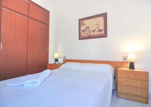 1 dormitorio con 1 cama grande y armario de madera en RNET - Port Estrella 21, en Roses