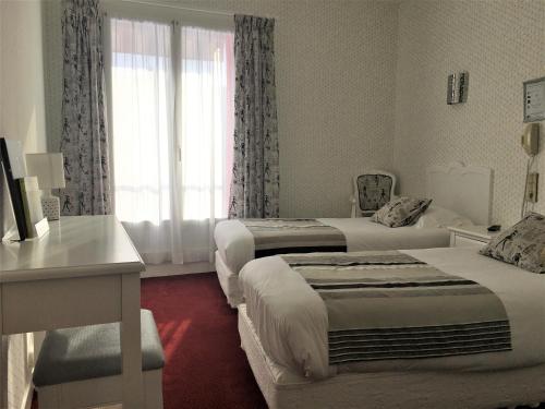 a hotel room with two beds and a window at Hôtel Restaurant Le Grillon in Chambon-sur-Lac