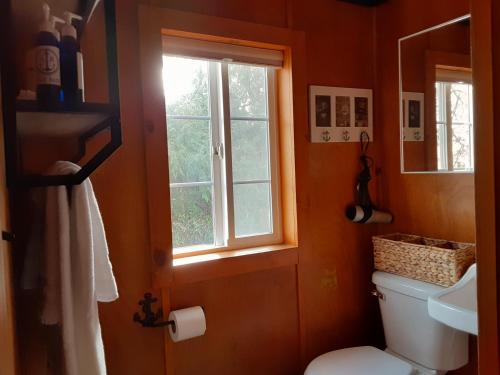 a bathroom with a toilet and a window at Anchor Inn Resort in Lincoln City