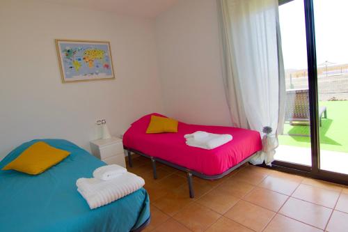 two twin beds in a room with a window at The Wind's Breath, perfect for relaxing getaway in La Oliva