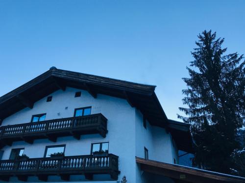 a white building with a balcony and a tree at Haus Jochbergerstrasse 116 in Kitzbühel