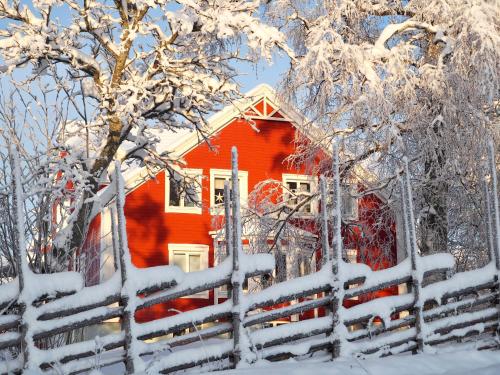 a red house with a fence covered in snow at Sörbygården Bed & Breakfast in Brunflo
