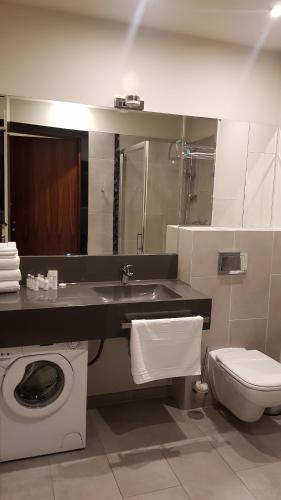 a bathroom with a toilet and a sink and a washing machine at Apartament prywatny 327 w Diune Resort in Kołobrzeg