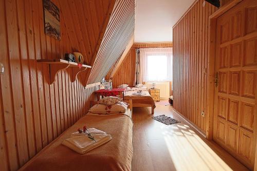 two beds in a room with wooden walls at Leśne Zacisze in Murzasichle