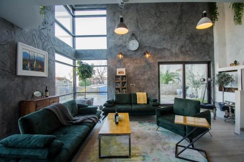 a living room with green furniture and a large window at Seafront Villa with Private Pool & Beach in Kotor Bay, Villa Viborg in Kotor