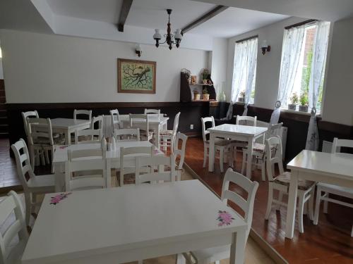 un comedor con mesas blancas y sillas blancas en HOTEL HO2 POIANA MARULUI en Poiana Mărului