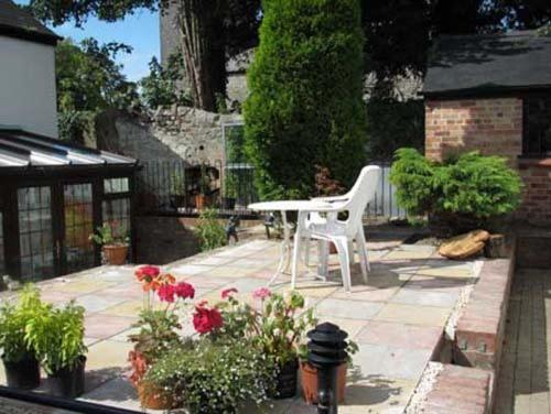 a patio with a white chair and a table and flowers at The Laurels Bed and Breakfast in Cardiff