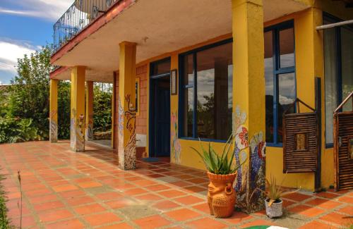 a yellow house with a porch with plants in front of it at Casa Encuentro Ecolodge, Outdoor Gym and Yoga in Guatapé