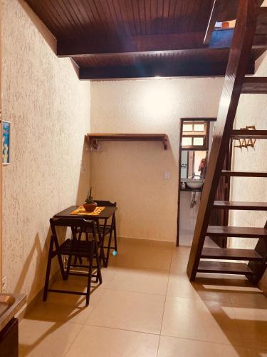 a room with a table and a stairs in it at Mandacaru Chalés e Suítes Itamambuca in Ubatuba