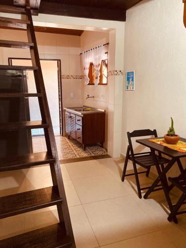 a living room with a ladder and a table and a kitchen at Mandacaru Chalés e Suítes Itamambuca in Ubatuba