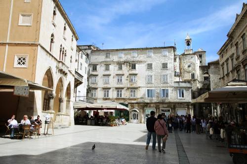 un grupo de personas caminando por una calle con una torre del reloj en Palace Wall Residences, en Split