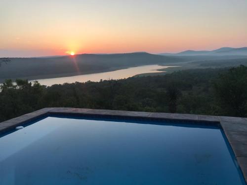 a swimming pool with a sunset in the background at Fish Eagles View - on game farm close to pilansberg in Tiokweng