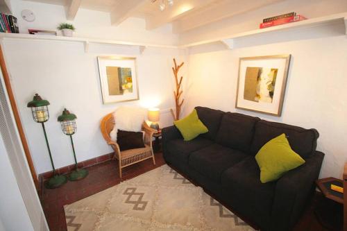 a living room with a black couch and yellow pillows at Galisteo Getaway - Courtyard - Near Railyard in Santa Fe
