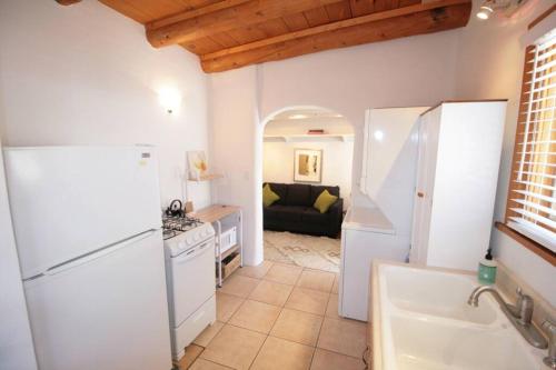 a kitchen with a white refrigerator and a living room at Galisteo Getaway - Courtyard - Near Railyard in Santa Fe