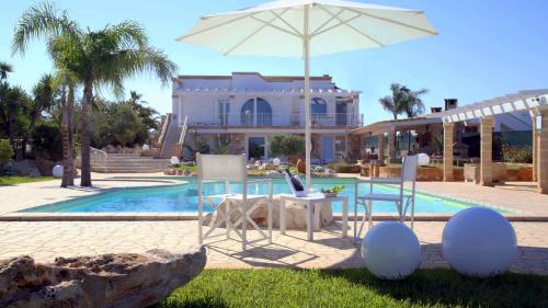 a white umbrella and chairs next to a pool at Villa Liquattruvienti in Leuca