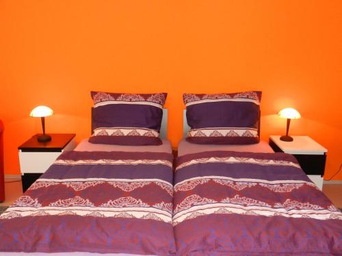 1 dormitorio con 2 camas con paredes de color naranja y 2 lámparas en Ferienwohnung Hameln Jasmin, en Hameln