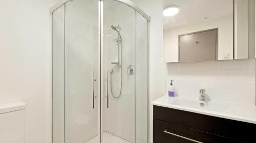 La salle de bains blanche est pourvue d'une douche et d'un lavabo. dans l'établissement Residence du Lac by Staysouth, à Queenstown